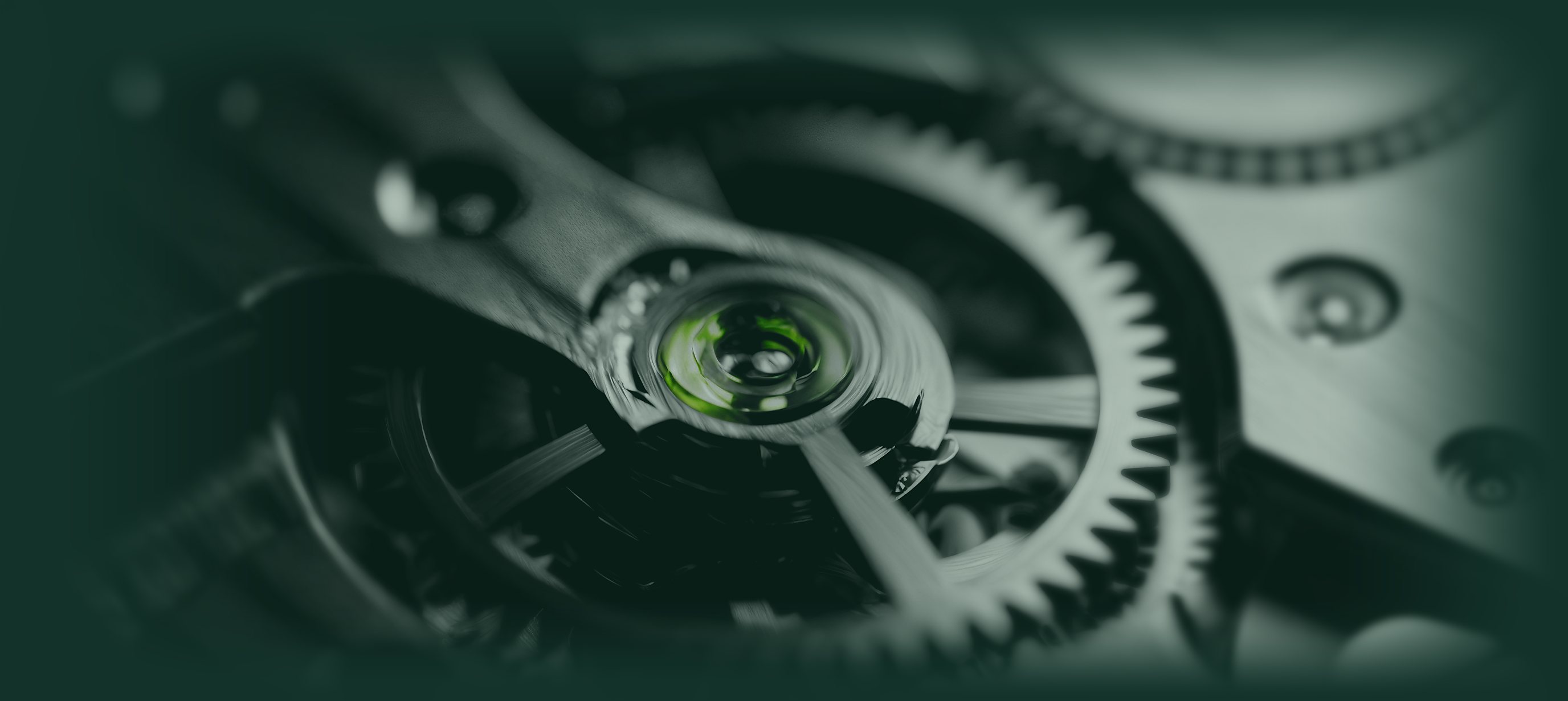 Il movimento di un orologio visto da vicino: ingranaggi dโacciaio e, al centro, una pietra verde.